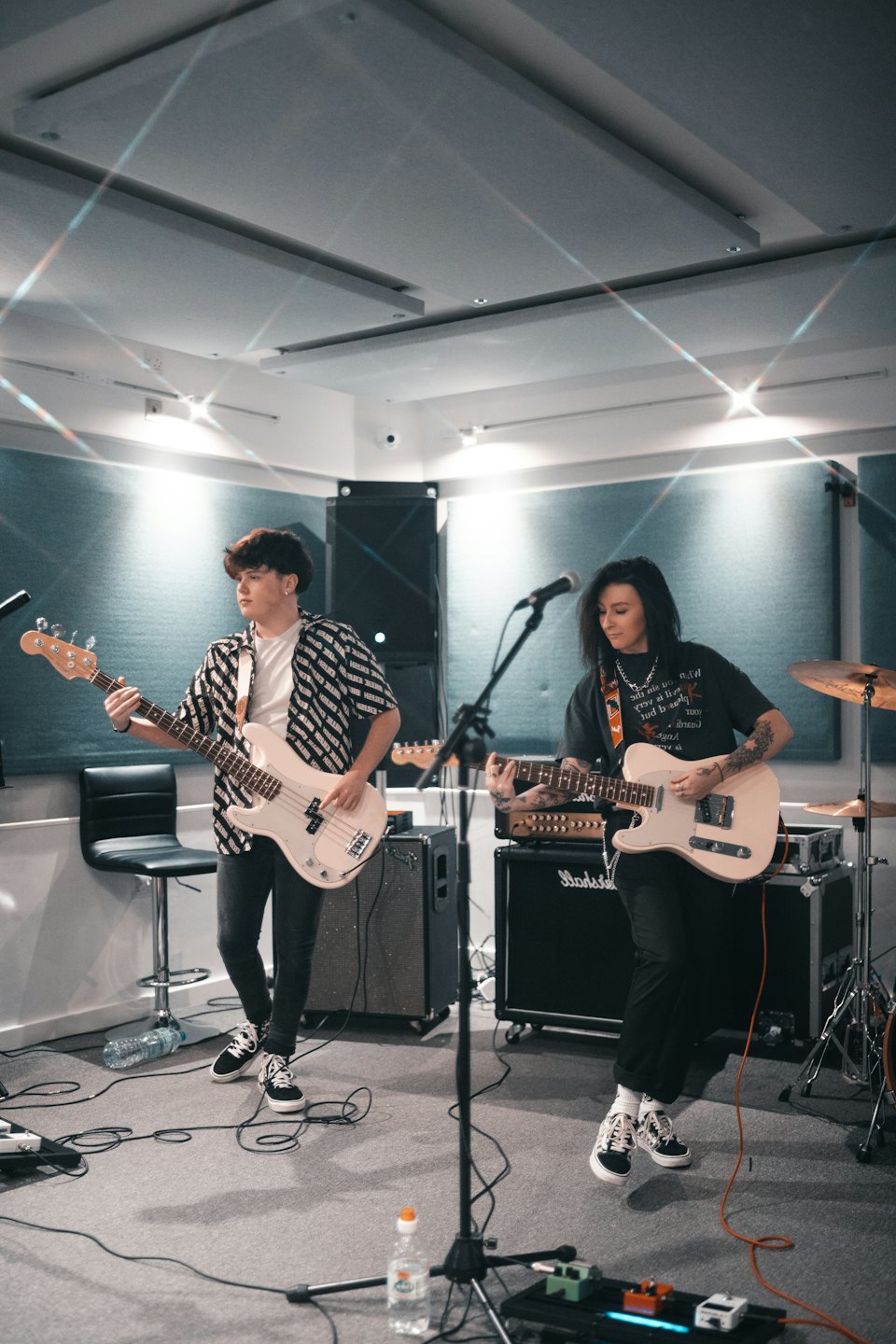Two musicians playing guitars in a modern recording studio.